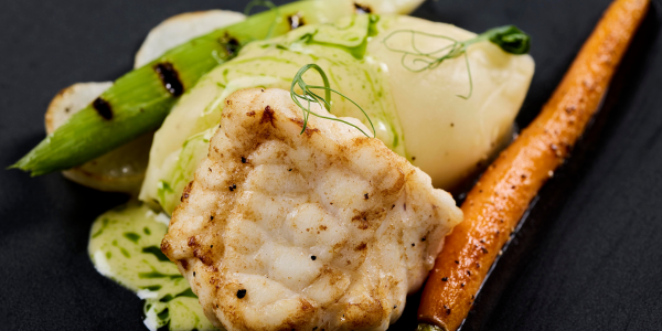 Pan-seared monkfish with herb pomme purée, baby vegetables and split mustard beurre blanc